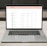 A laptop on a table displaying a cryptocurrency trading platform. The screen lists various cryptocurrencies along with their buy and sell values, spread percentages, and 24-hour change percentages. The keyboard and touchpad of the laptop are visible, set against a neutral background with a sofa in the back.